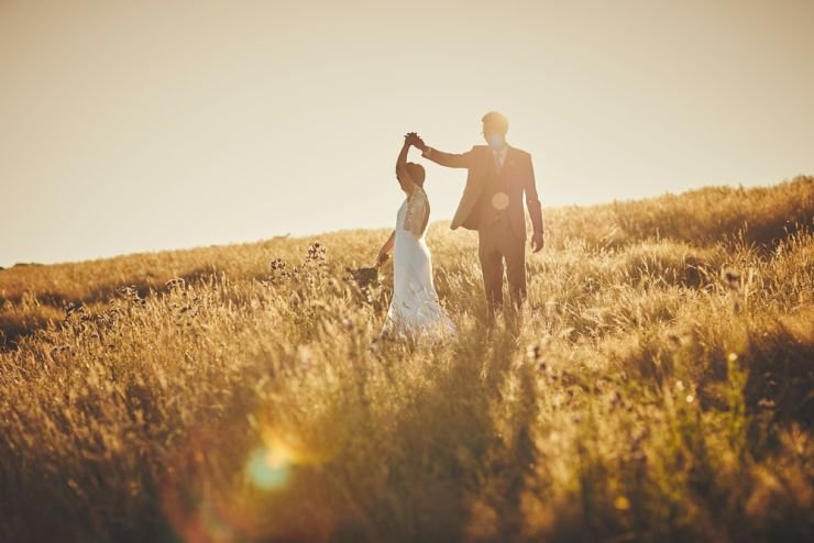 wedding photography of a bride and groom dancing in a corn filed at sunset