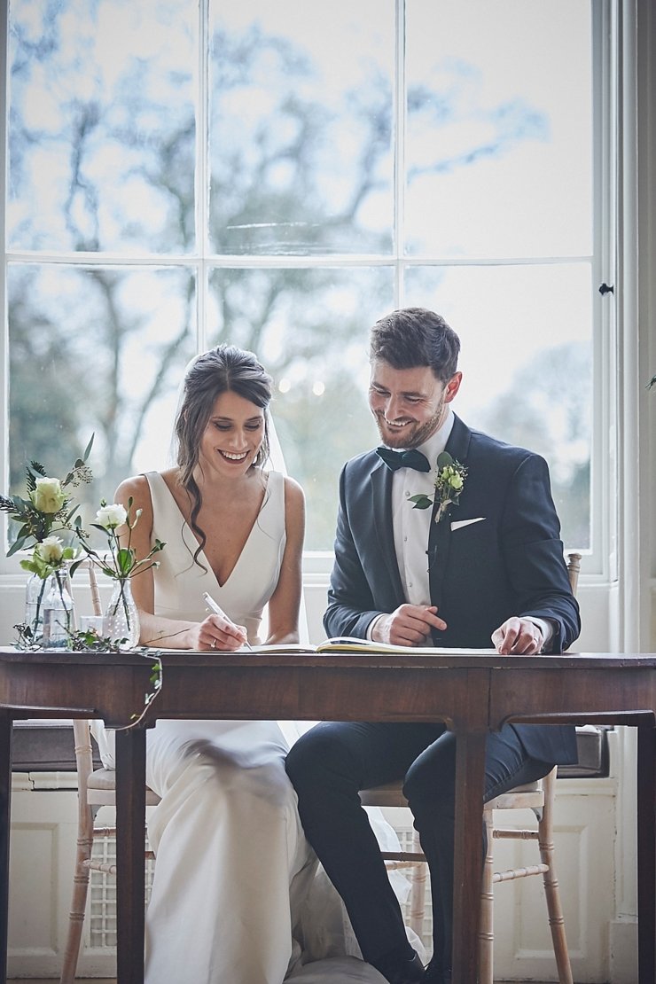 bride and groom happy signing register at wedding ceremony at small devon wedding