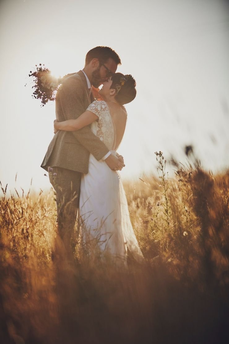 bride and groom kissing in Devon field at golden hour