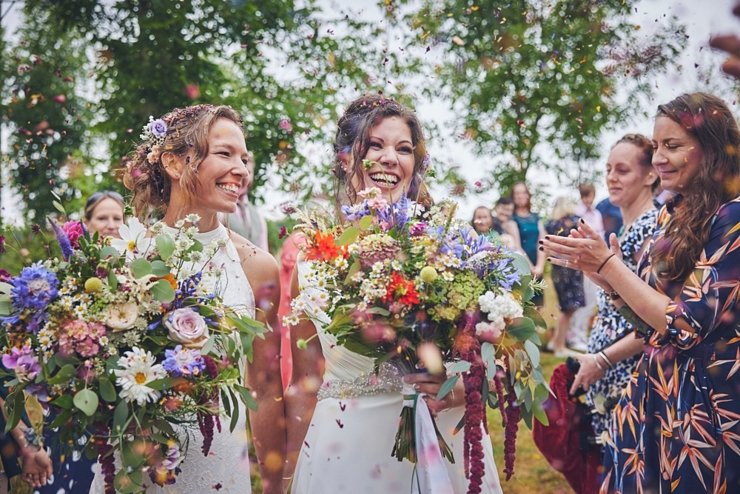 bride and bride laughing with confetti at higher Holcombe Devon