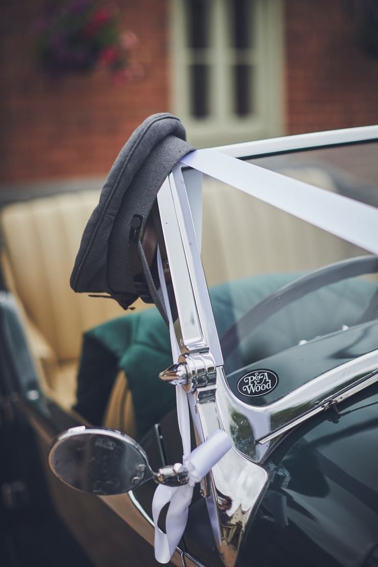 chauffeur's hat hanging on vintage wedding car window in Exeter