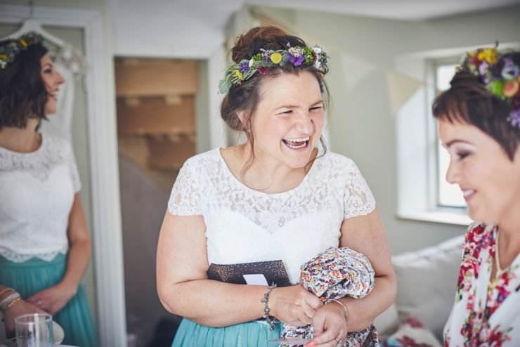 bridesmaid laughing wearing white lace top and green skirt and bright flower crown