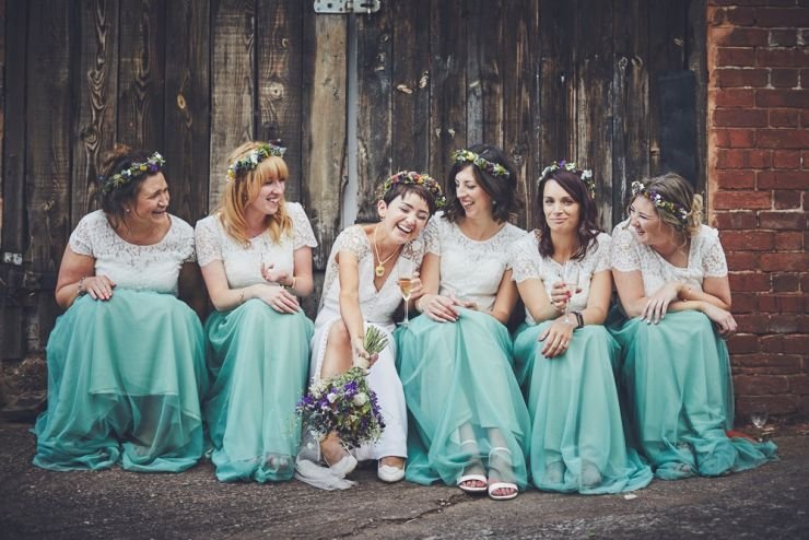 fun wedding photography of bridesmaids and bride sat together laughing at a Devon wedding at West Town farm