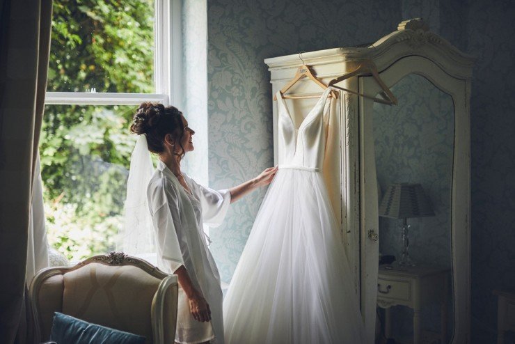 bride looks at her wedding dress before her beach wedding at tunnels beaches in devon