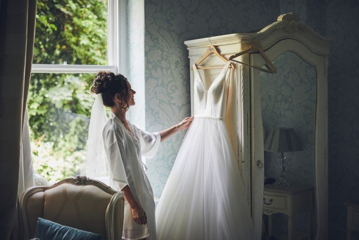 bride looks at her wedding dress before her beach wedding at tunnels beaches in devon