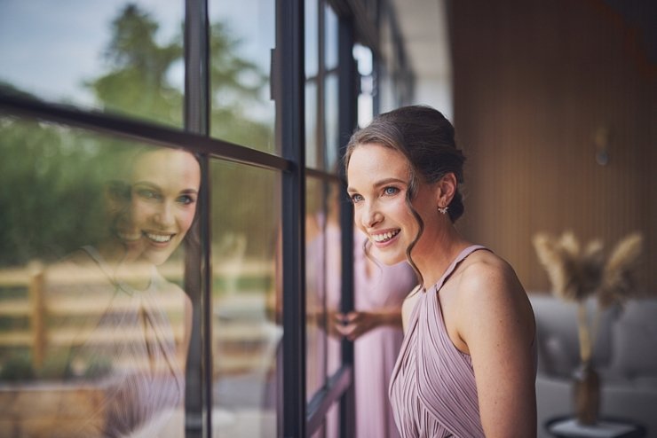 bridesmaid looking out of window smiling at Upton Barn near Exeter