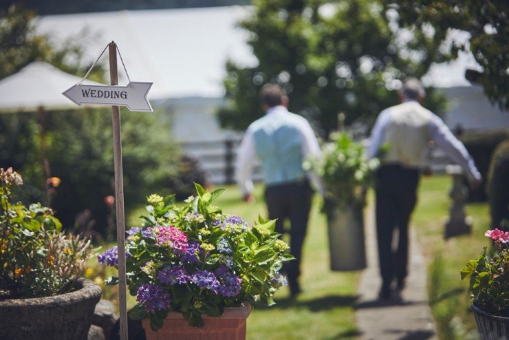 photography of country wedding showing wedding sign and ushers carrying flower urn.jpg