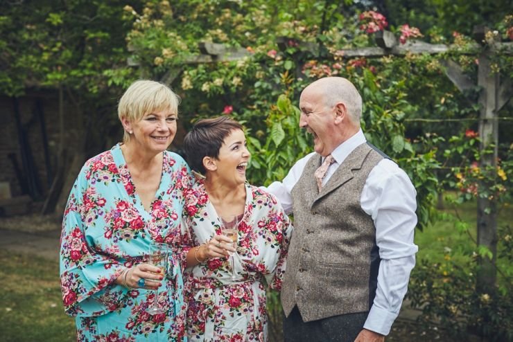 bride to be laughing with mum and dad at home before the Devon wedding ceremony 