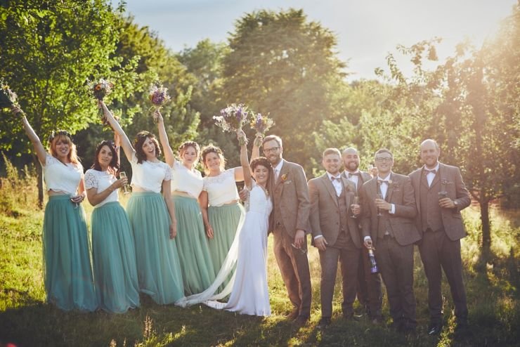 bride, bridesmaids, groom and groomsmen cheering and happy at golden hour in Devon