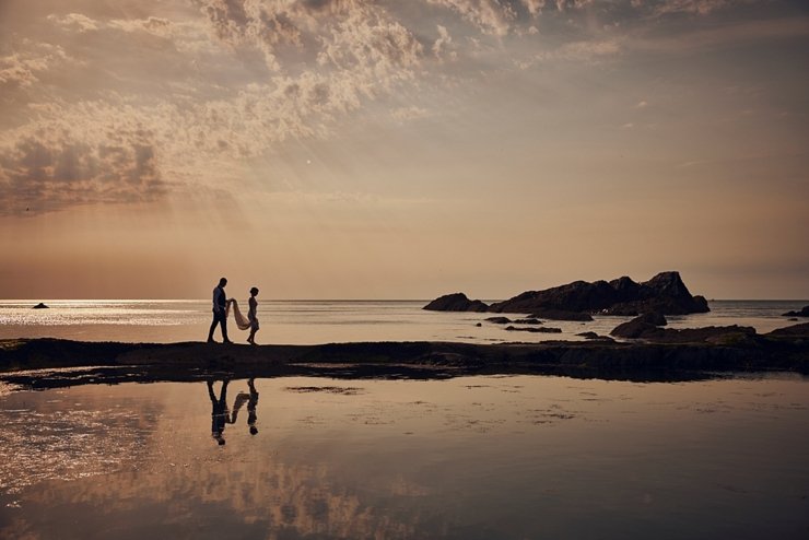couple walk at sunset on tidal pool wall at tunnels beaches 